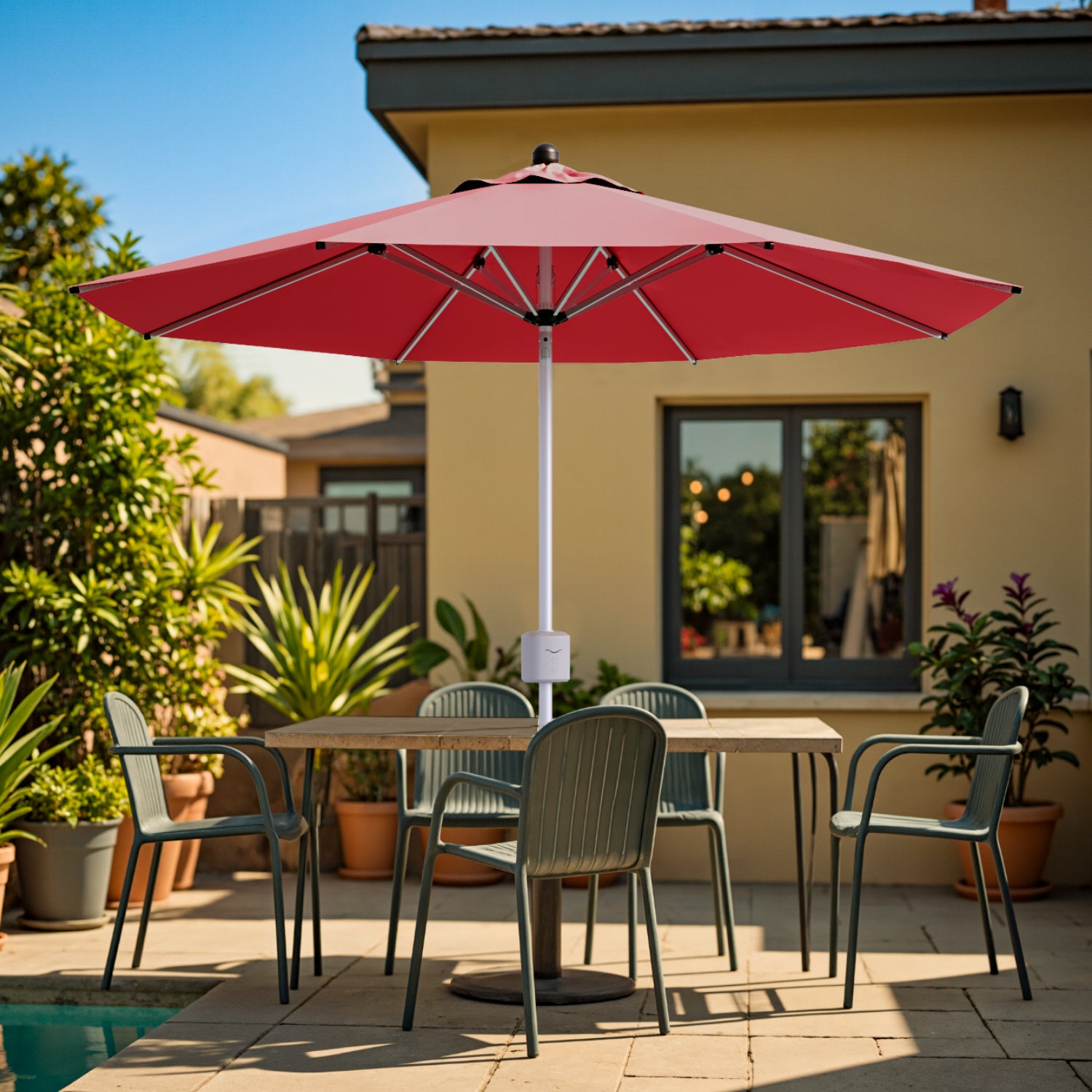 Red patio umbrella over a dining table with chairs on a sunny patio.