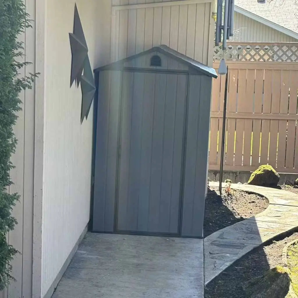 a fit-it 4x6 plastic storage shed in the corner against the wall in backyard